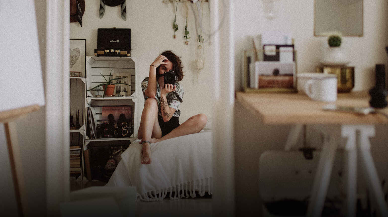 Person on chair with camera in a room with table and coffee mug.