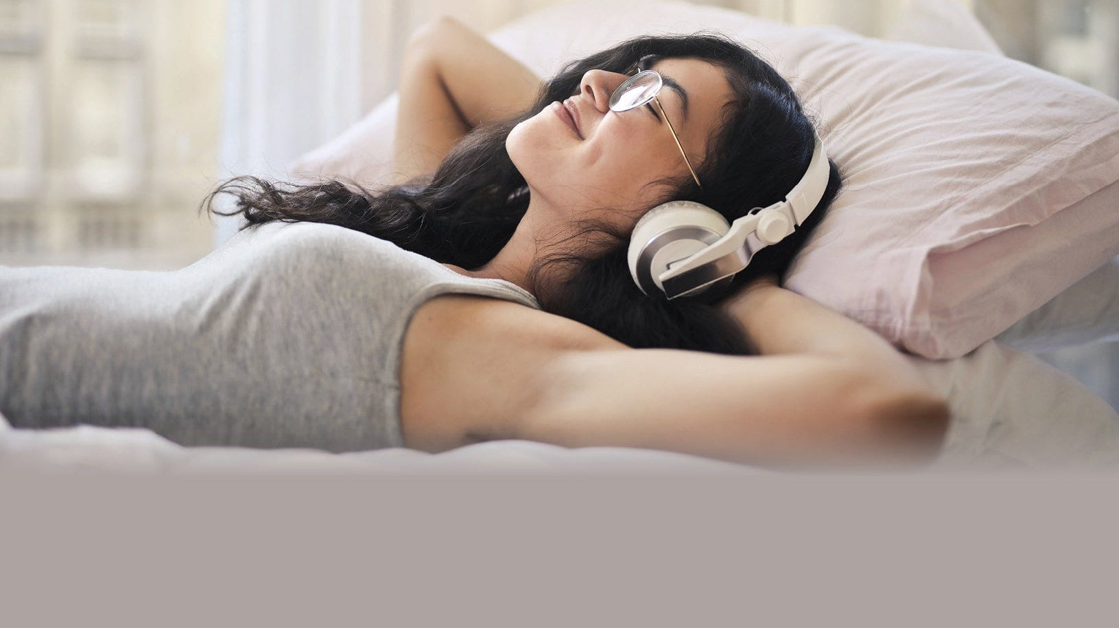 a woman lying on a bed relaxing with headphones.