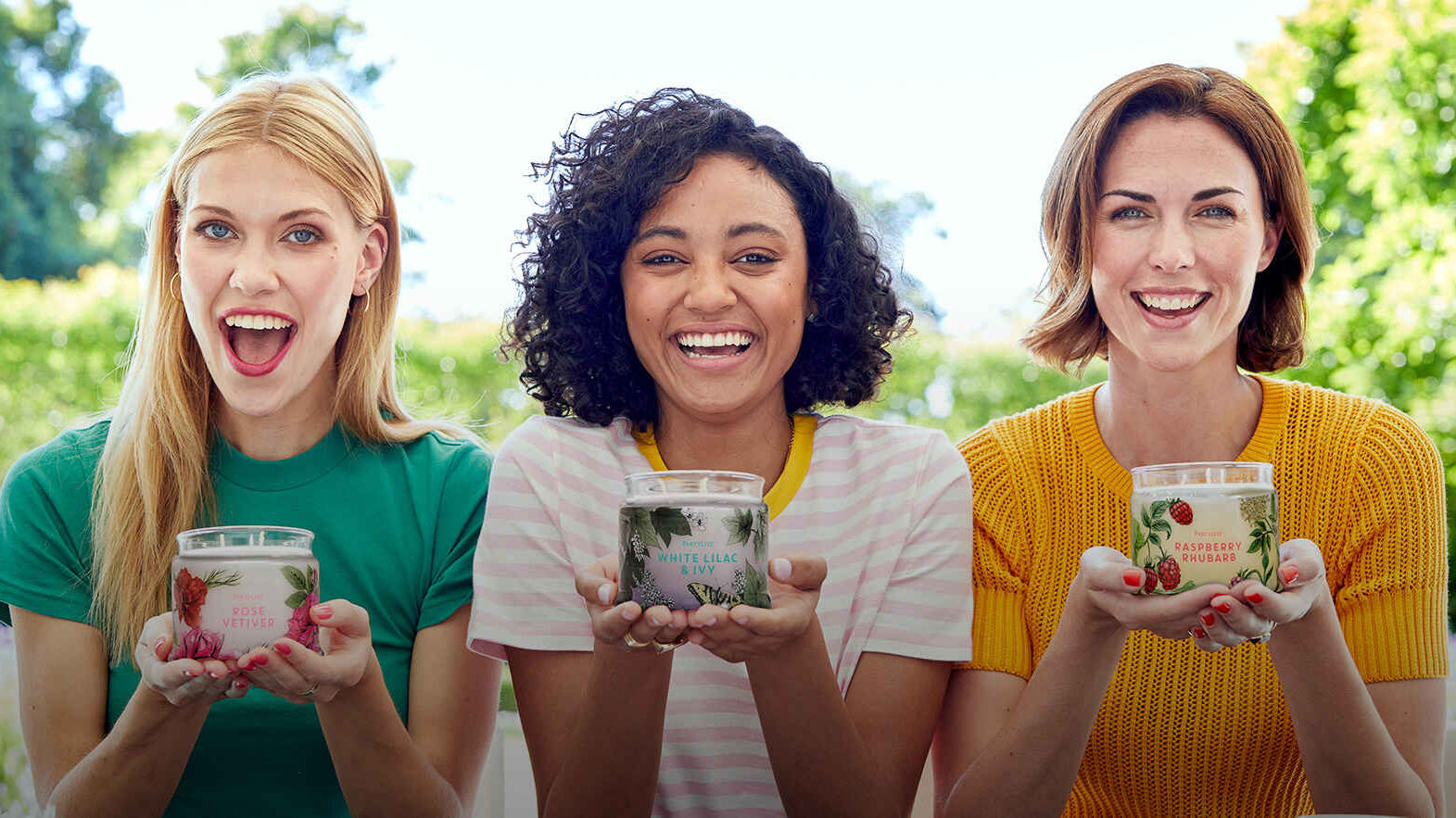 3 women each holding a PartyLite jar candle