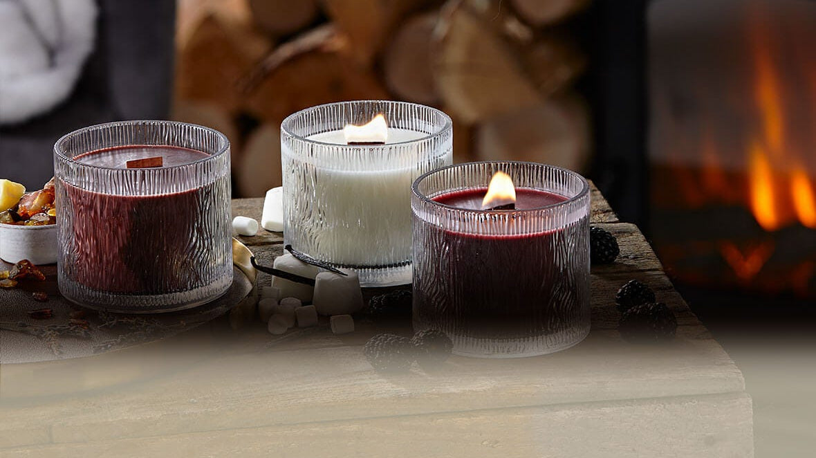 Three Wood wick jar candles on a table with a blurred background.