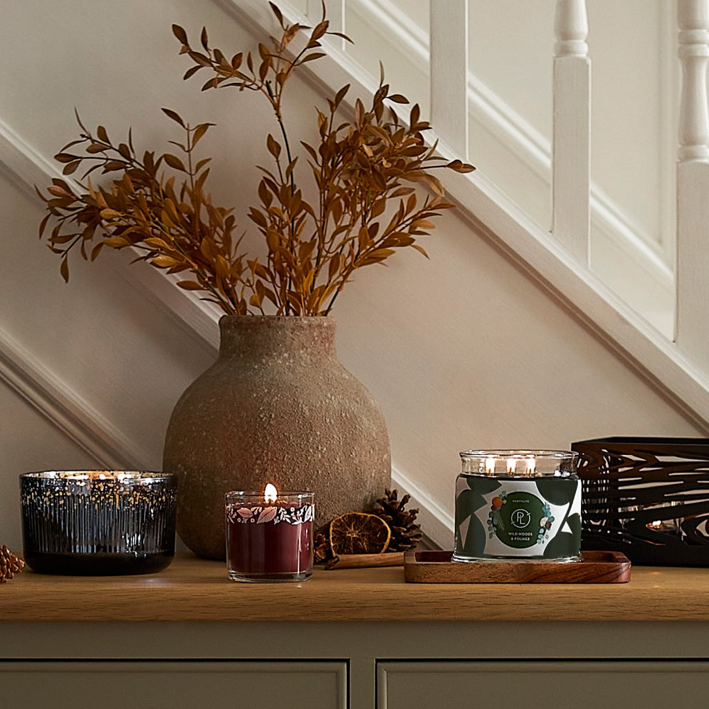 Sideboard with a wood grain hurricane, assorted jar candles, and a wood grain centerpiece.