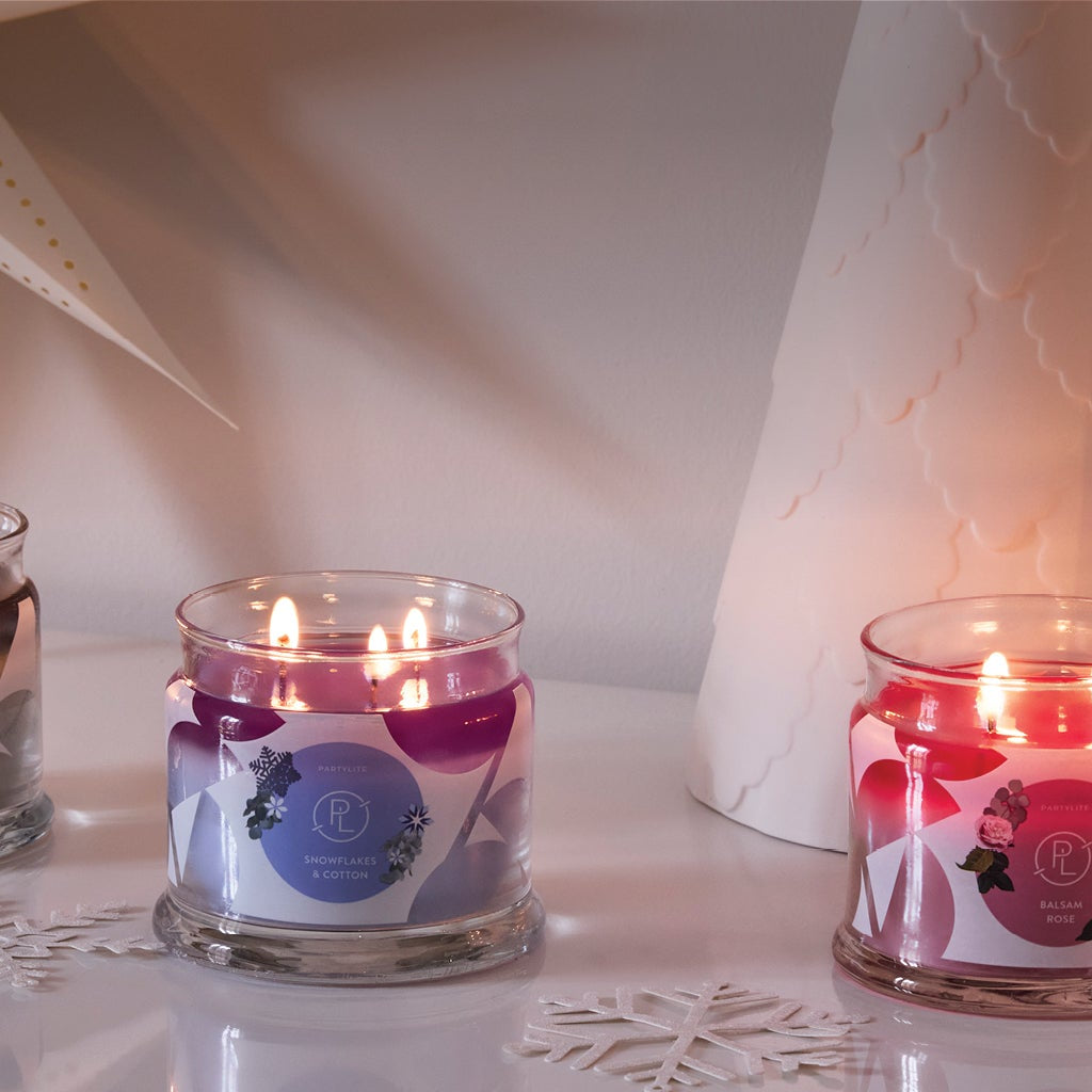 Three 3-Wick Jar candles with decorative white trees on a table.