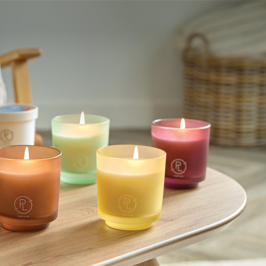 Coffee table with 5 Refillable Jar Candles and one Refill. Person in background is refilling a candle.
