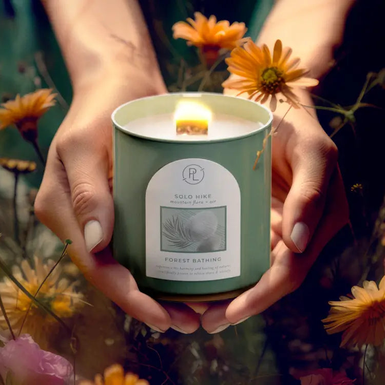 forest bathing jar candle held in a field of flowers