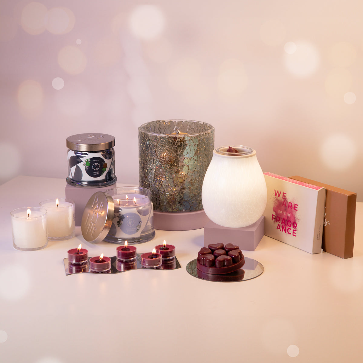 A collection of PartyLite gift items including various candles, holders, and a wax melt, displayed against a festive background.