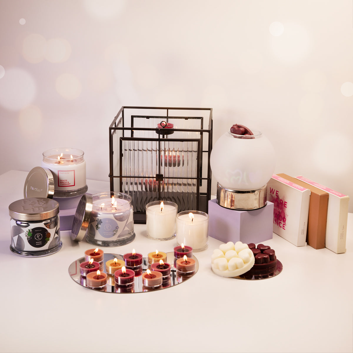 A collection of PartyLite candles and holders displayed with various tealights and a scent glow warmer, arranged on a table with a white background.