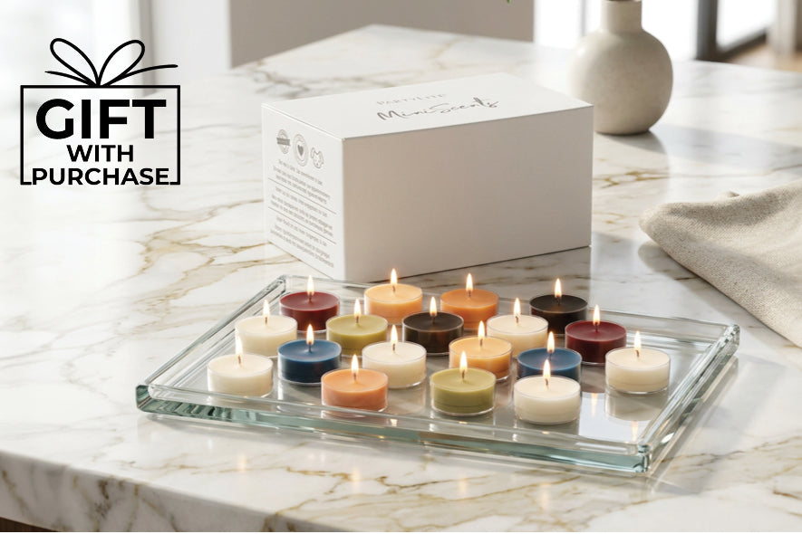 Various colored lit tealights on a glass tray on a kitchen worktop with the words "Gift with Purchase"