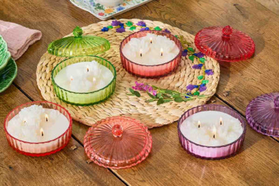 Collection of Garden Beauty Specialty Jar candles with lids on a woven mat on a wooden surface
