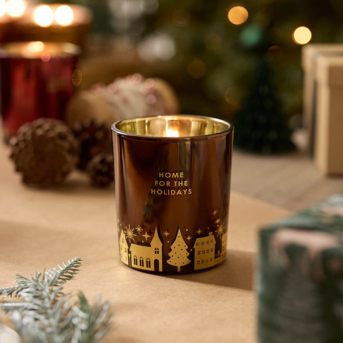 Home for the Holidays Jar - Holiday Spices, a brown shiny jar with gold decorative Holiday themed items along the bottom of the jar.