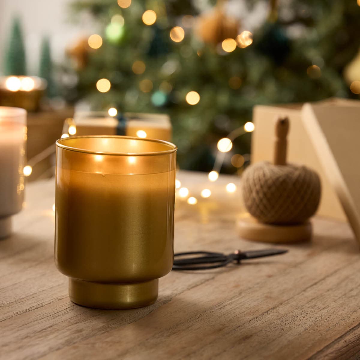 Iced Snowberries 2-Wick Specialty Jar Candle in a gold finish, on a wooden surface.
