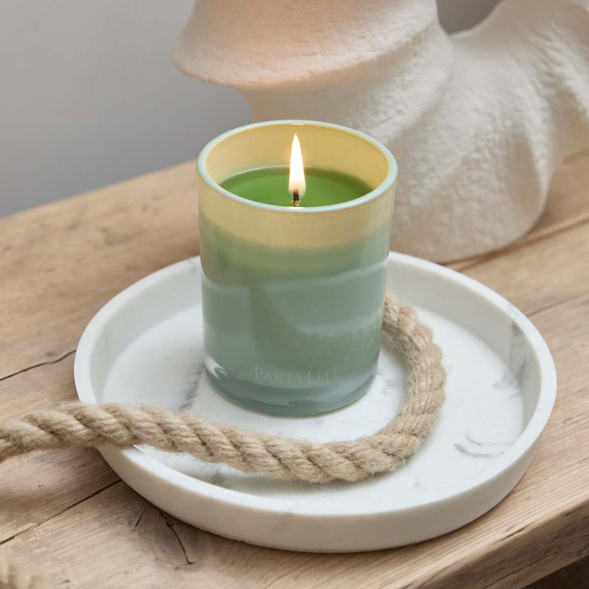 Seagrass Eucalyptus Escential Jar™ Candle on a white marbled tray with a rope on a wooden surface.