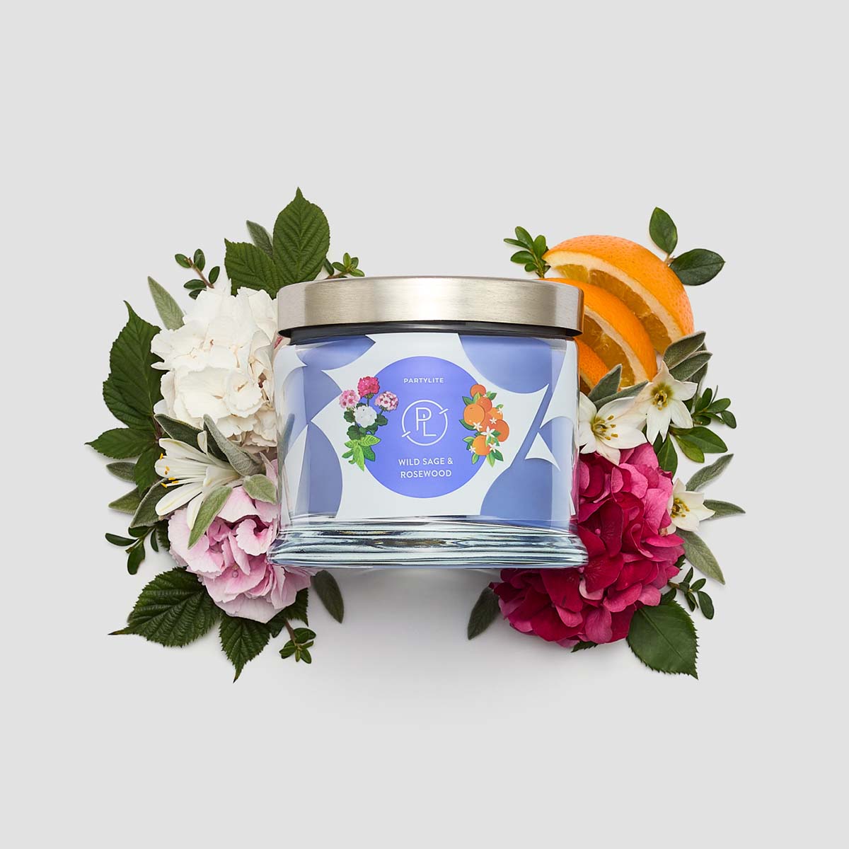 Wild Sage & Rosewood 3-Wick Jar Candle surrounded by flowers on a white background.