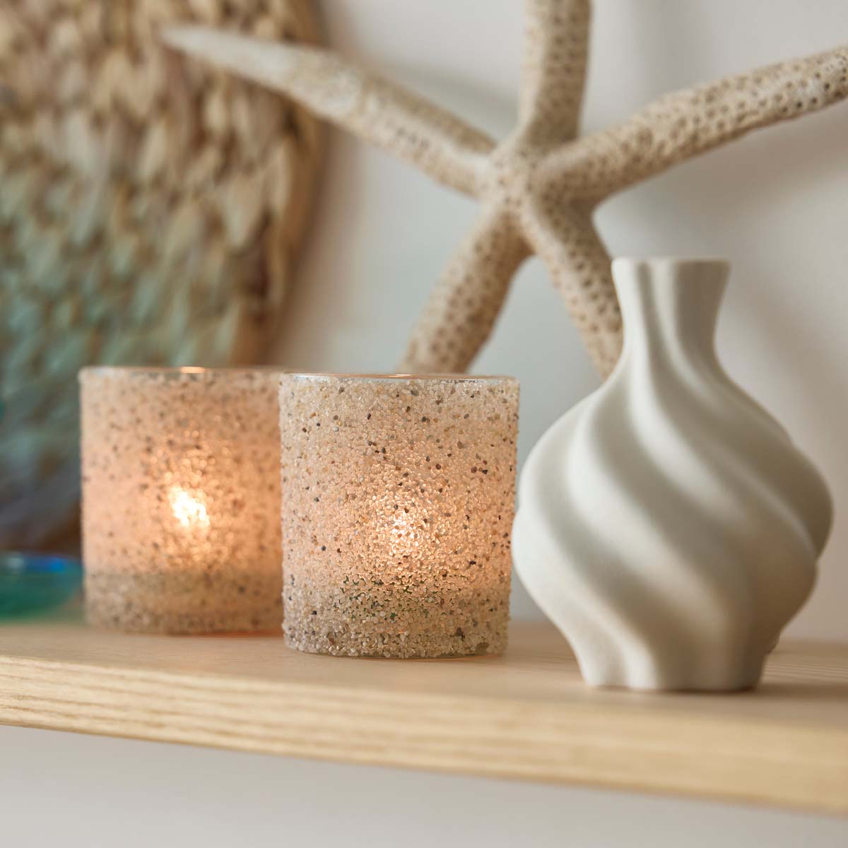Sand Dune Tealight/Votive Holder Pair on a wooden shelf with a star shaped decorative item in the background.