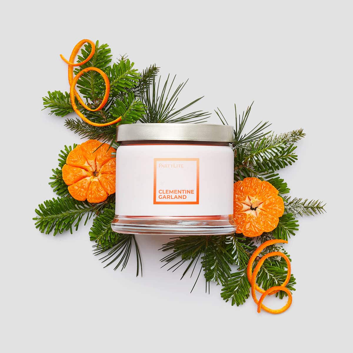 Clementine Garland 3-wick jar candles, surrounded by fruits and fir leaves against a white background.