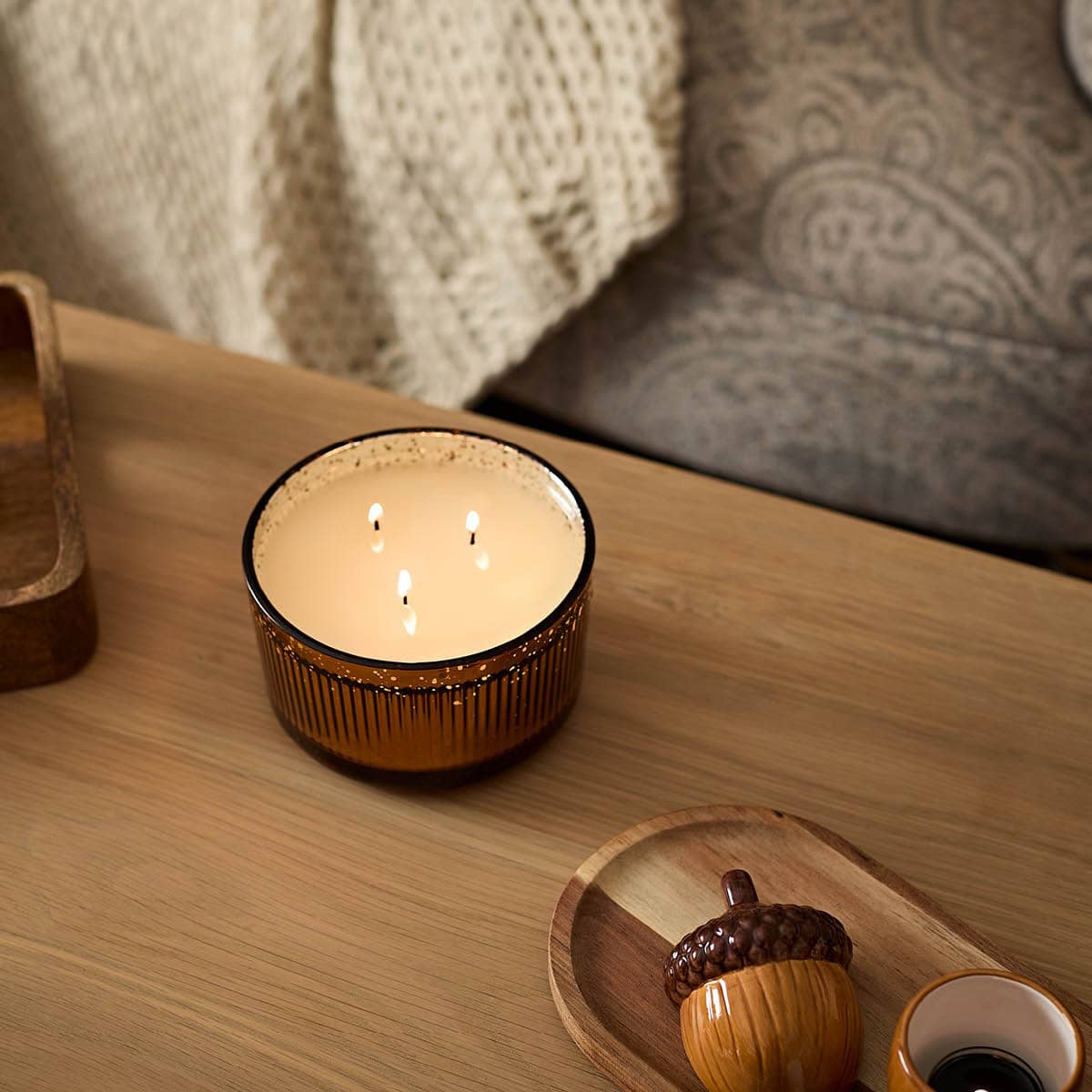 Woodland Pumpkin 3-Wick Ripple Jar Candle lit on a wooden table.