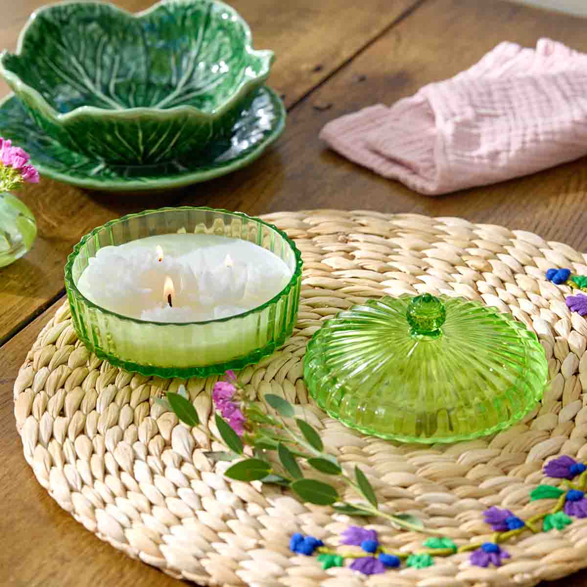 Garden Beauty Specialty Jar - Sunlit Greenhouse, green glass jar with the lid off on a woven table mat on a wooden table.