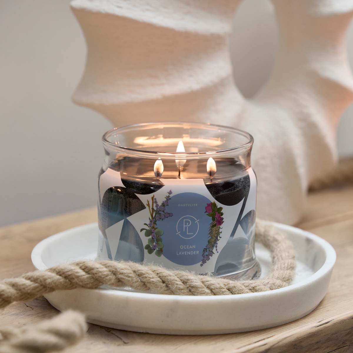 Ocean Lavender 3-wick Jar Candle lit on a white tray with a rope on a wooden surface.