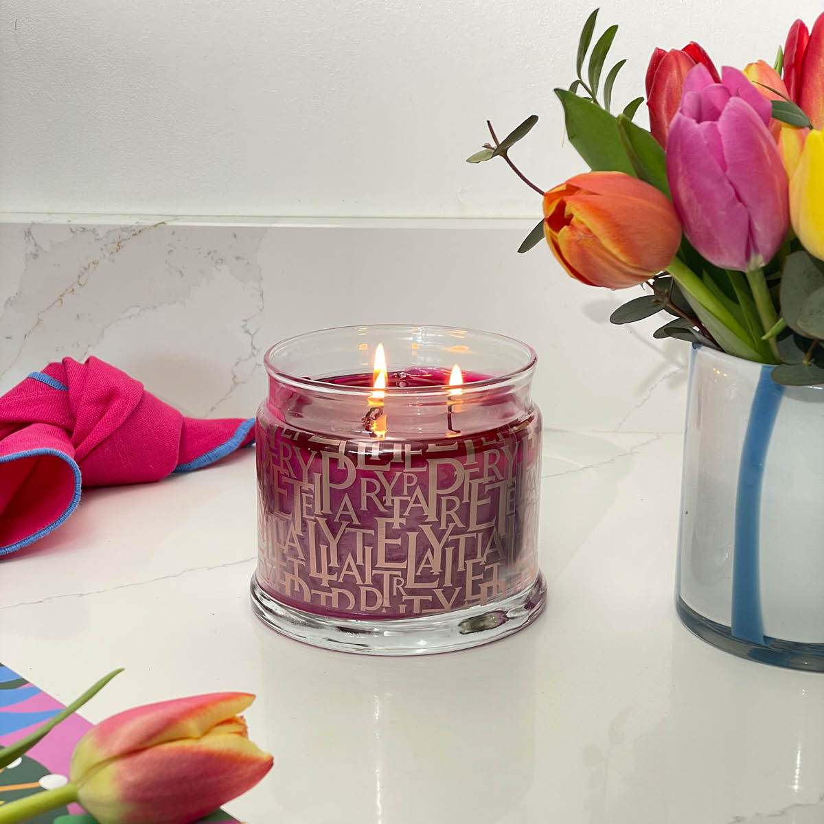 Berry Blast 3-Wick Jar Candle on a kitchen counter with a vase of tulips.