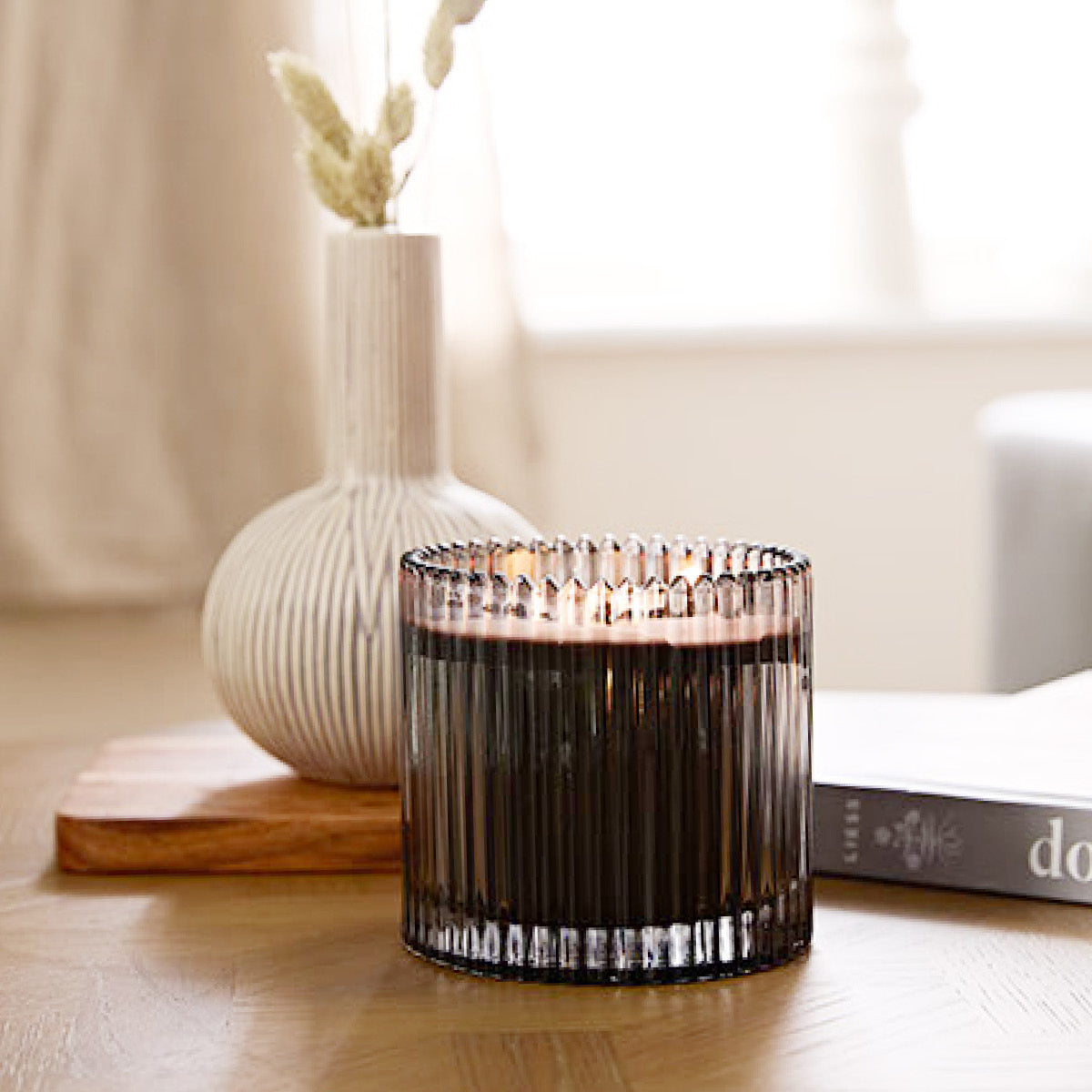 Fig Fatale Jar Candle in a textured glass holder on a wooden surface with a blurred background.