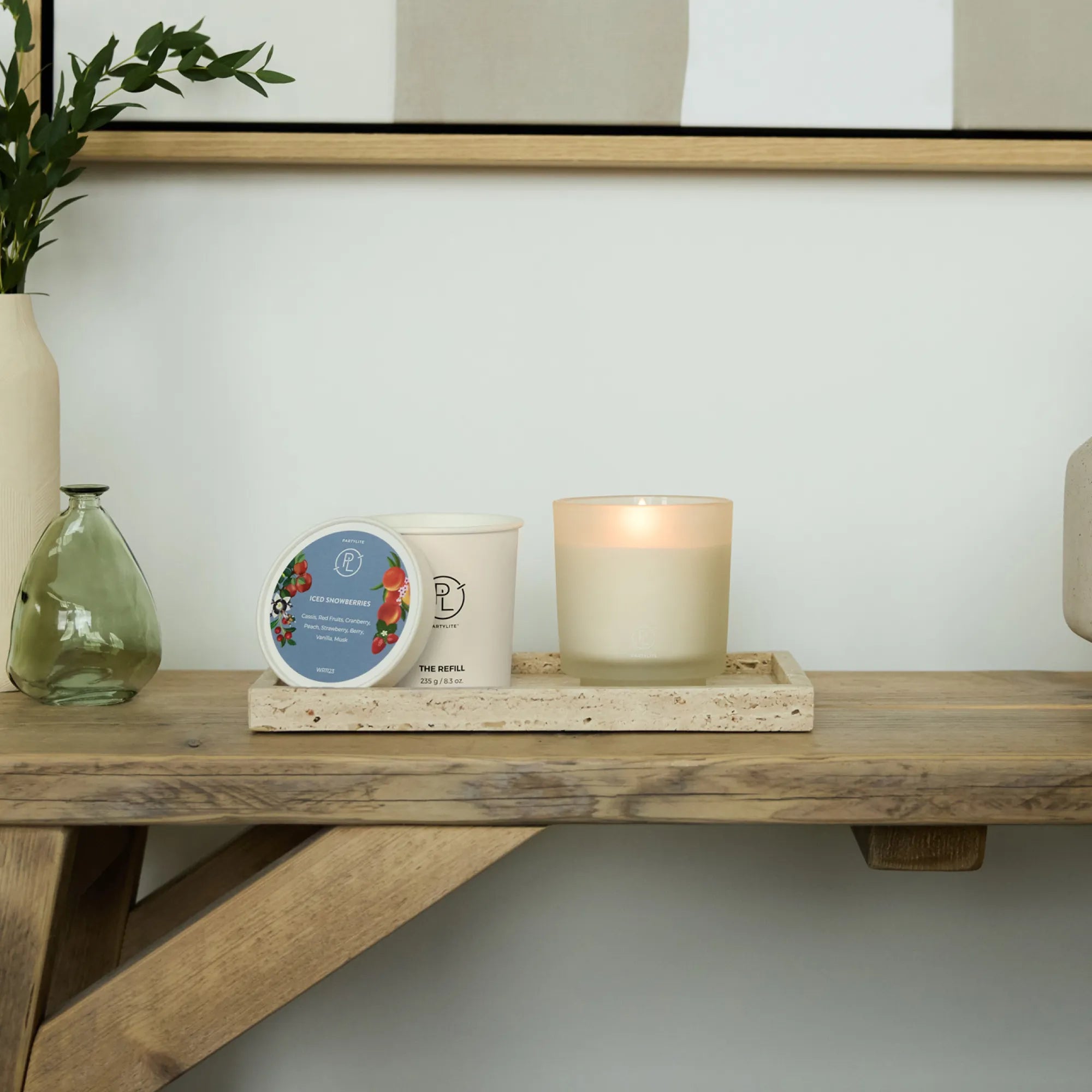 Iced Snowberries Refillable Jar Candle shown with the refillable candle on a speckled tray on a wooden table against a light background