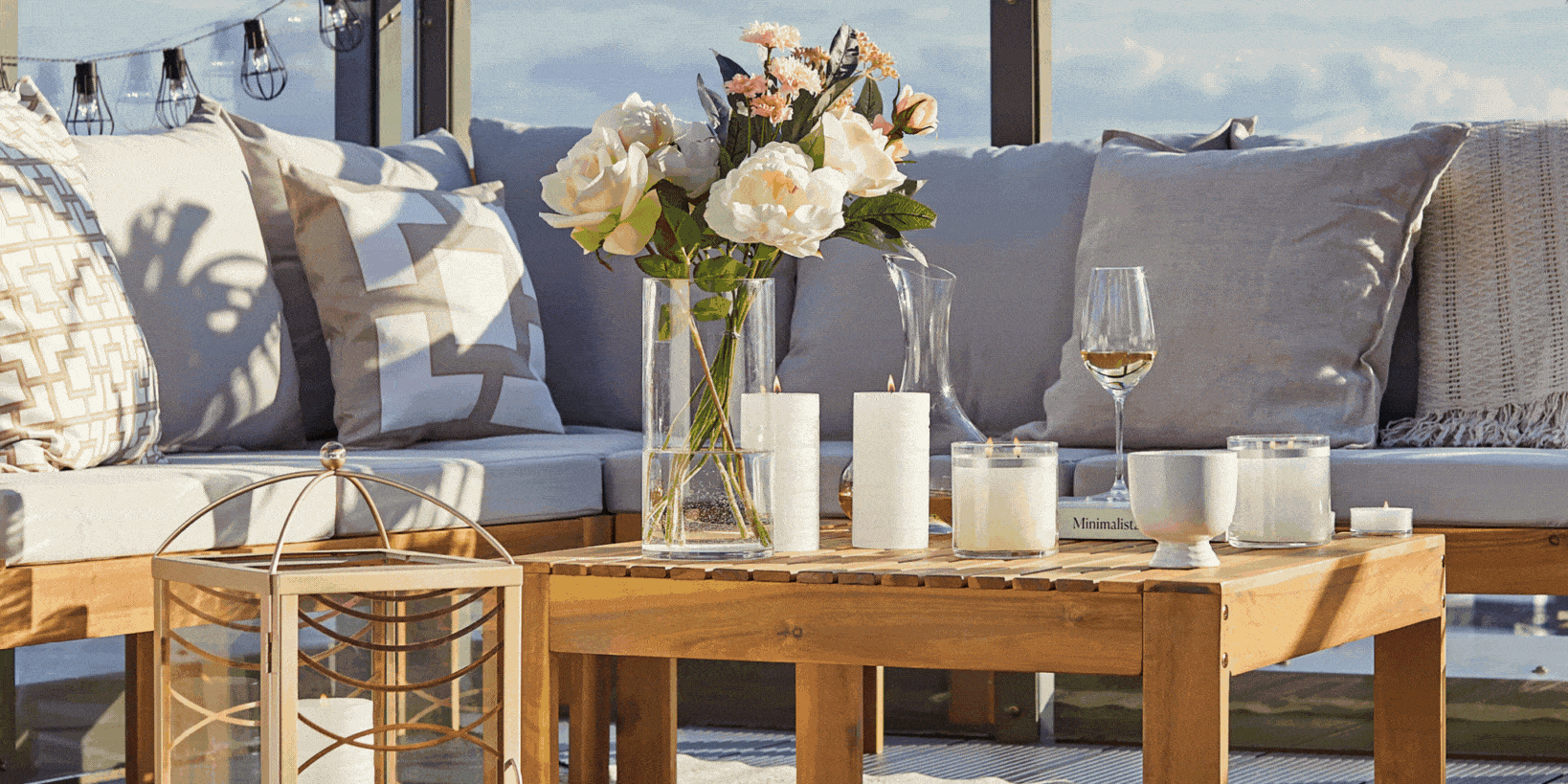 GloLite candles shown on a table during the day and night, with a vase of flowers and a sofa in the background