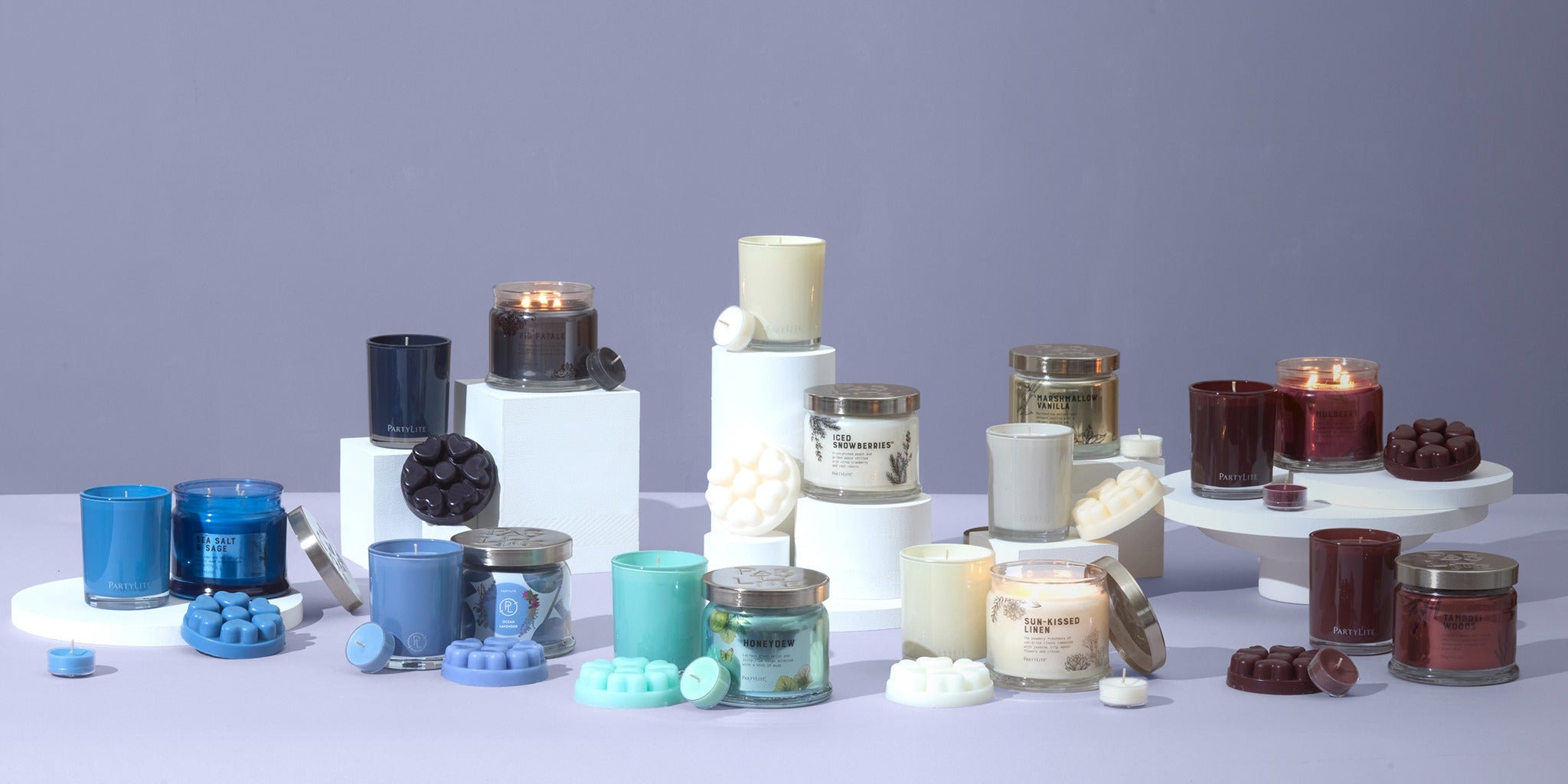 Nine candle collections displayed on raised columns or stands or on a light surface