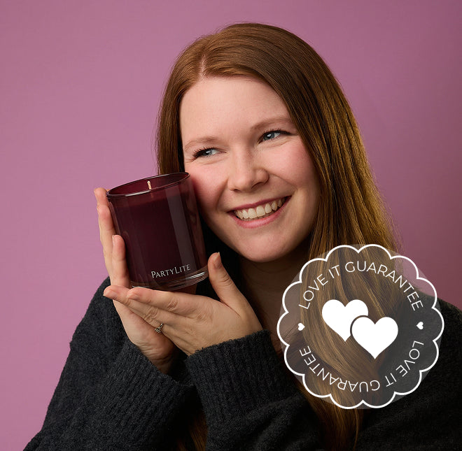 Woman holding a Party Lite candle with a 'Love It Guarantee' badge on a pink background.