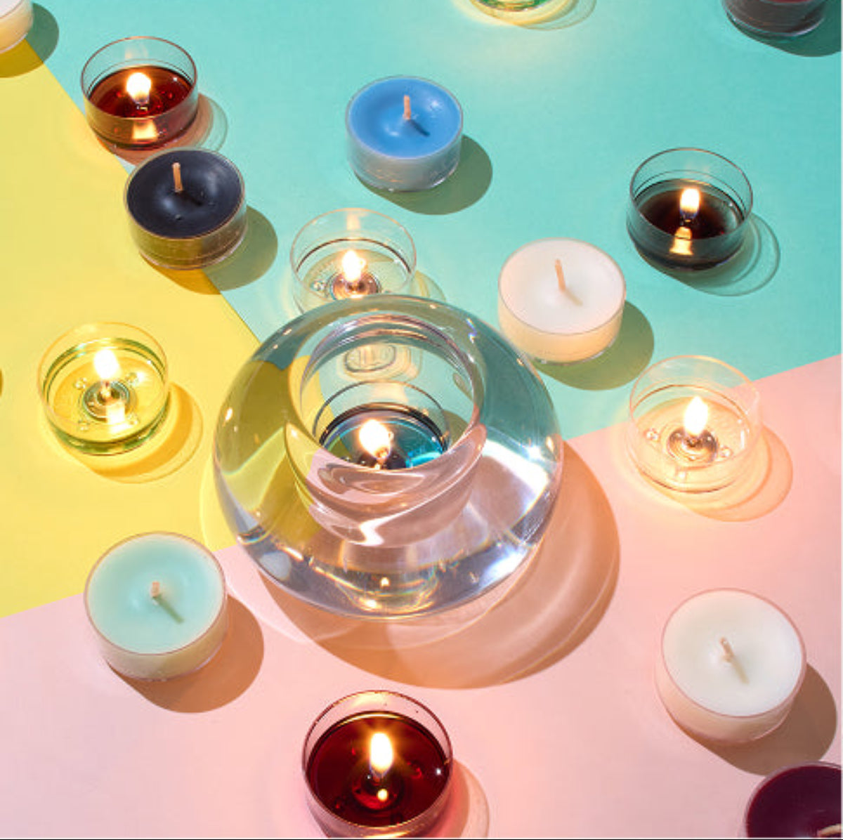 Colorful tealight candles and the raindrop candle holder on a gradient background