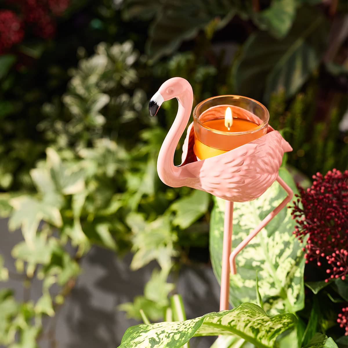 Flamingo Garden Incense Spike shown in a garden with plants and a lit tealight