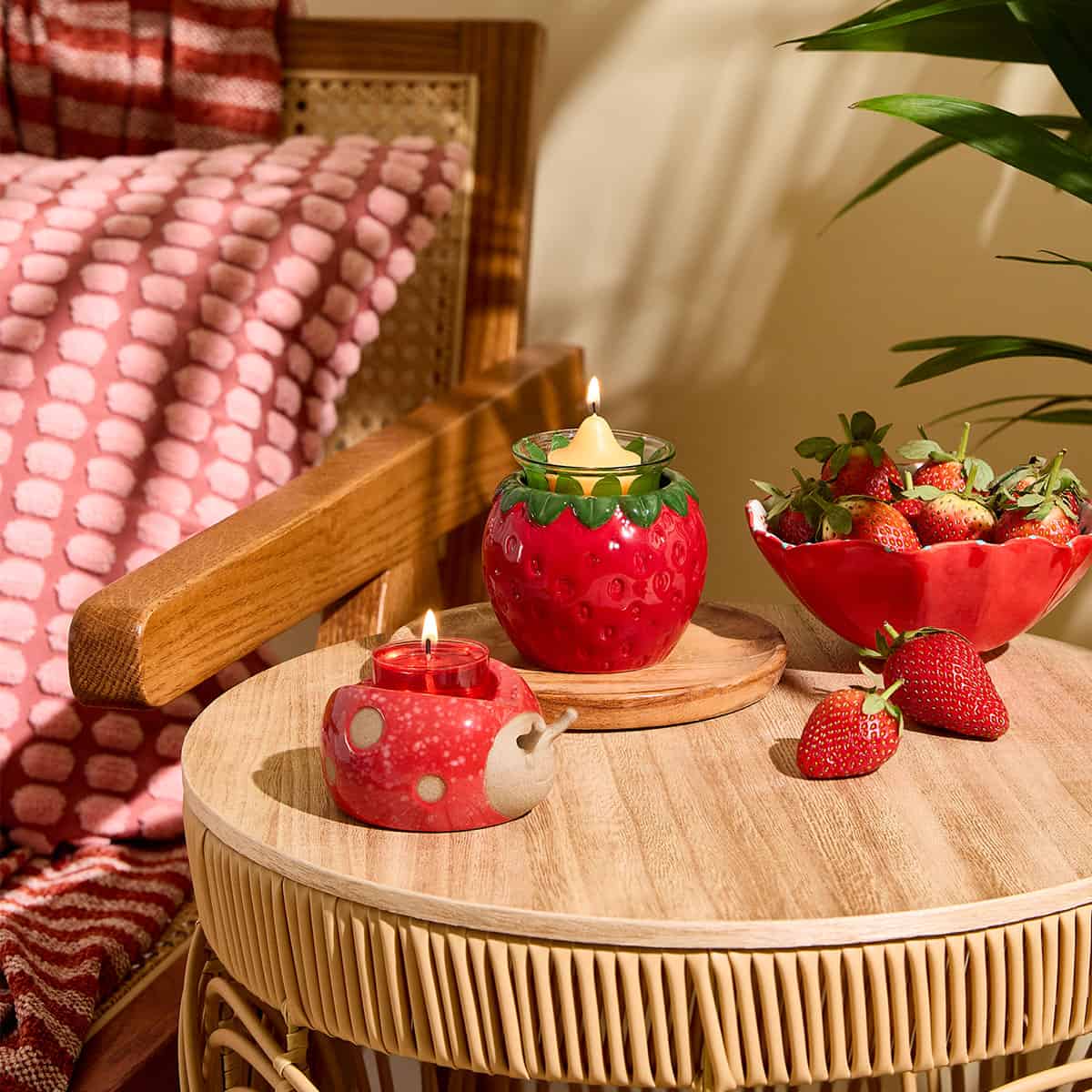 Loveable Ladybug Tealight Holder shown with our Strawberry Tealight Holder and a bowl of Strawberries in the background on a wooden table