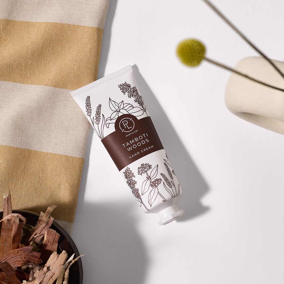 Tamboti Woods Hand Cream shown with a small ceramic bowl of wood chippings and a stripy cloth on a white background