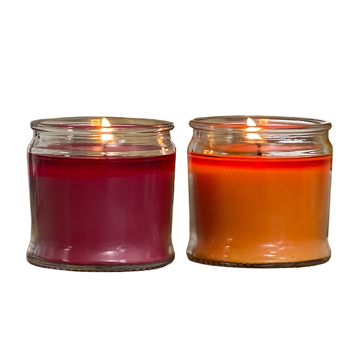 Two glass candle jars side by side, one with a red wax candle and the other with an orange wax candle, both without lids.