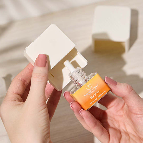 Smart Plug in refill bottle in Happy Fragrance shown in a person hand on a light background