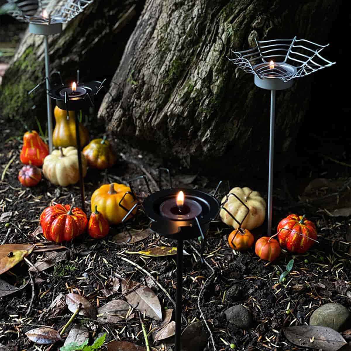 Halloween Garden Incense Spike, showing two pairs in silver with spider web, and balck with a spider, shown outside with lit tealights.