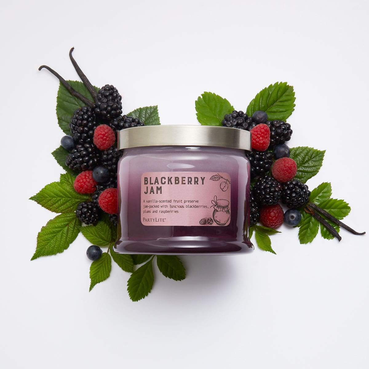 Blackberry Jam 3-Wick Jar Candle surrounded by blackberries, raspberries and leaves against a white background.