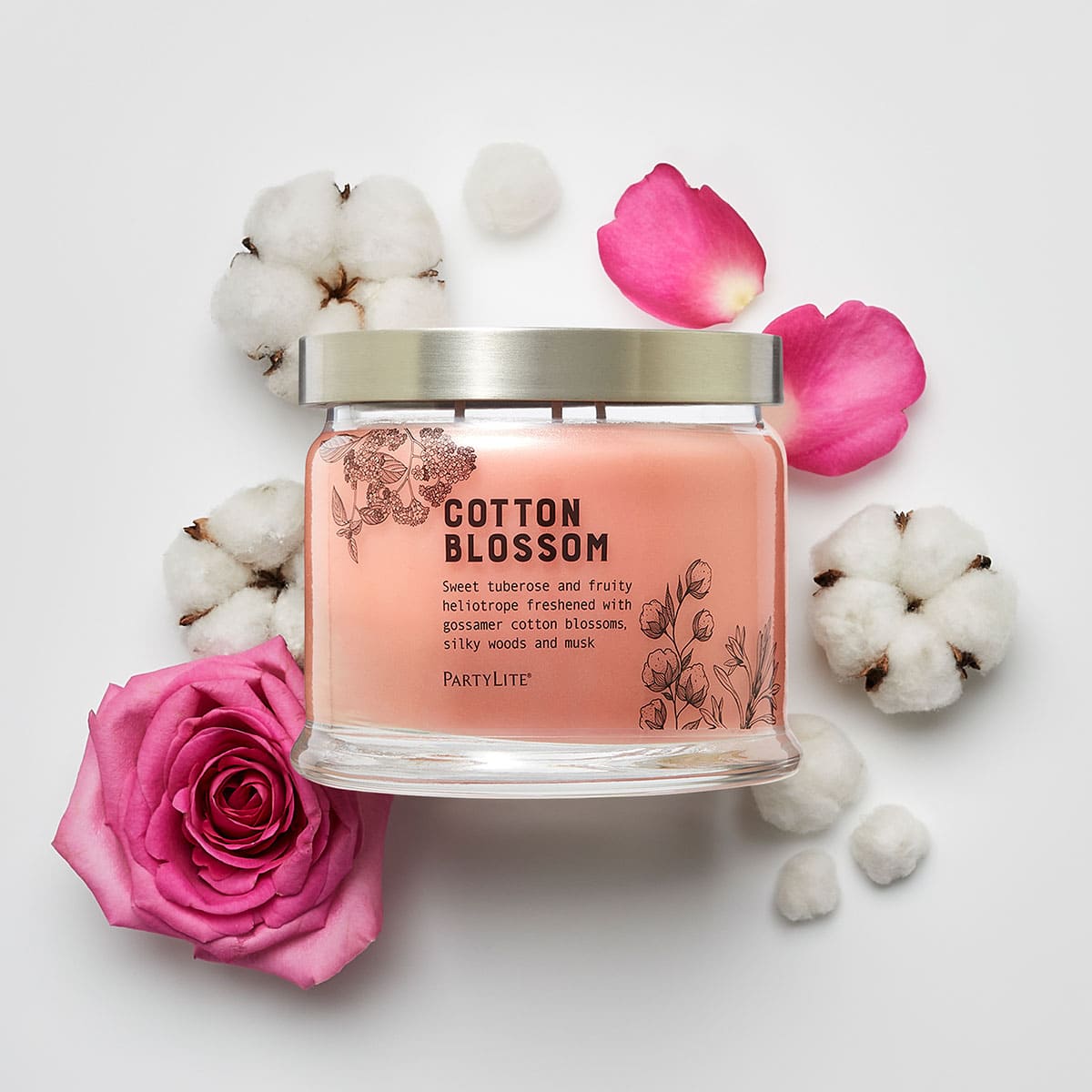 Cotton Blossom 3-Wick Jar Candle surrounded by pink roses and cotton blossom against a white background.