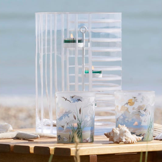 Linear Lines Glass Hurricane Candle Holder with lit tealights shown with tealight holders on a wooden surface.
