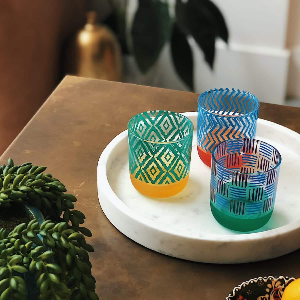 Tribal Chic Tealight Holder Trio colorful holders on a light tracy on a wooden table.