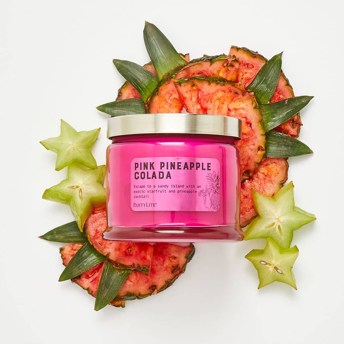 Pink Pineapple Colada 3 Wick Jar Candle surrounded by fruits against a white background.