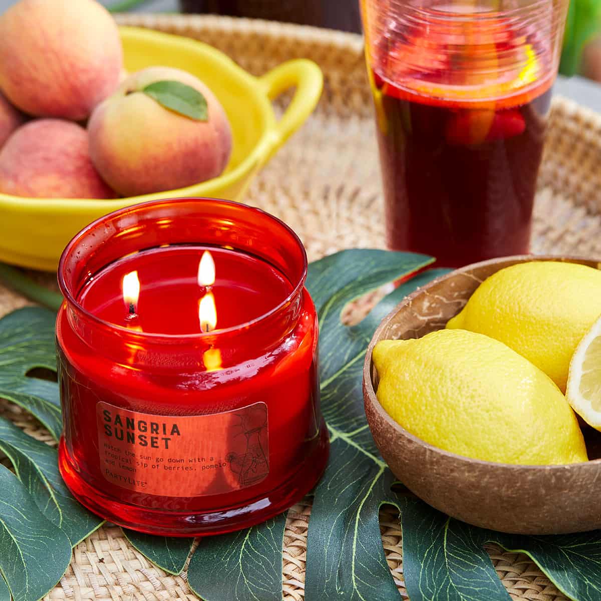 Sangria Sunset 3 Wick Jar Candle on a table setting with bowls of fruit.