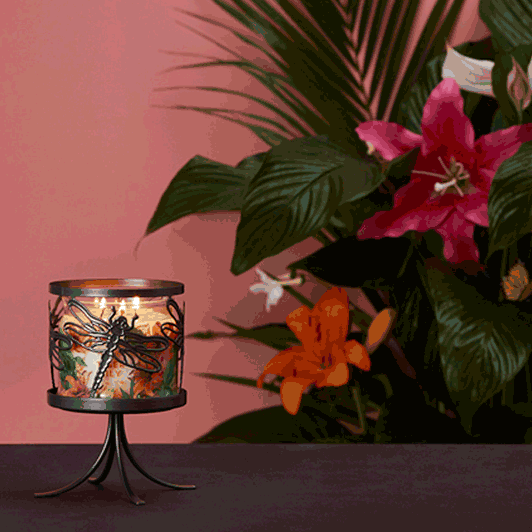 Dragonfly Jar Candle Sleeve shown with a lit 3-wick jar candle with colorful flowers and leaves in the background.