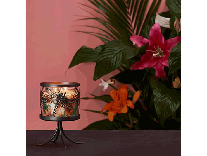 Dragonfly Jar Candle Sleeve shown with a lit 3-wick jar candle with colorful flowers and leaves in the background.