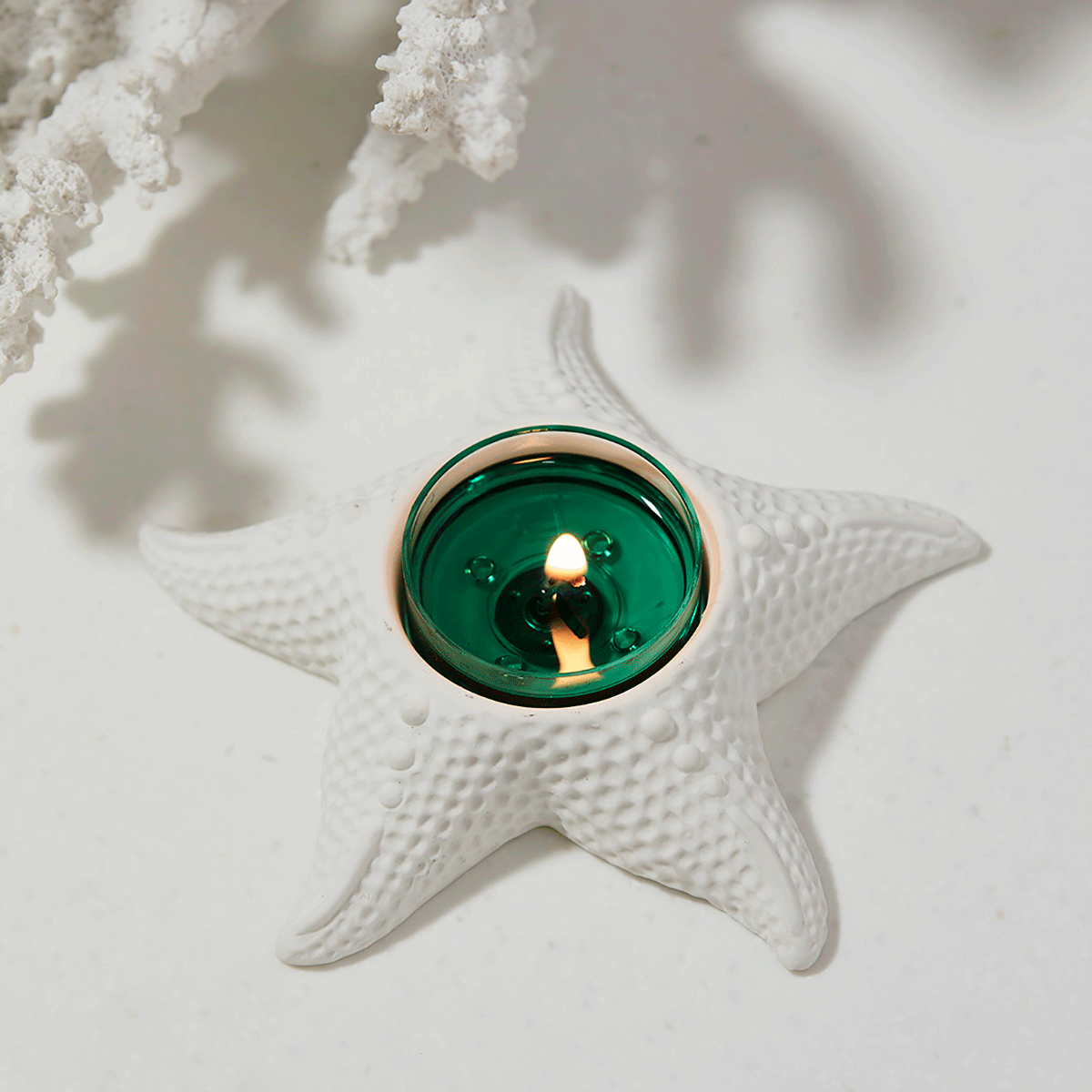 White Starfish Tealight Holder shown with a lit tealight candle, against a white background.