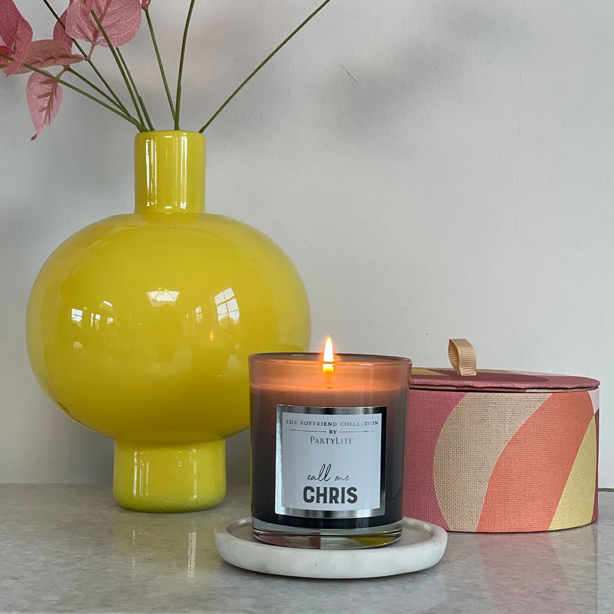 "Chris" Boyfriend Jar Candle – Tamboti Woods on a light tray with a yellow vase against a light background.