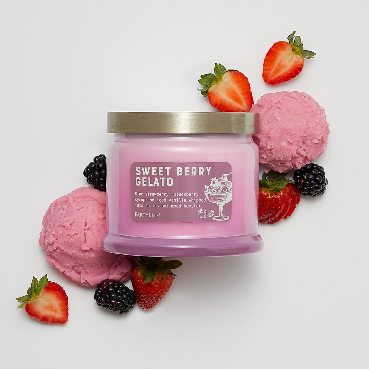 Sweet Berry Gelato 3-Wick Jar Candle surrounded by pink icecream and strawberries and blackberries on a white background.