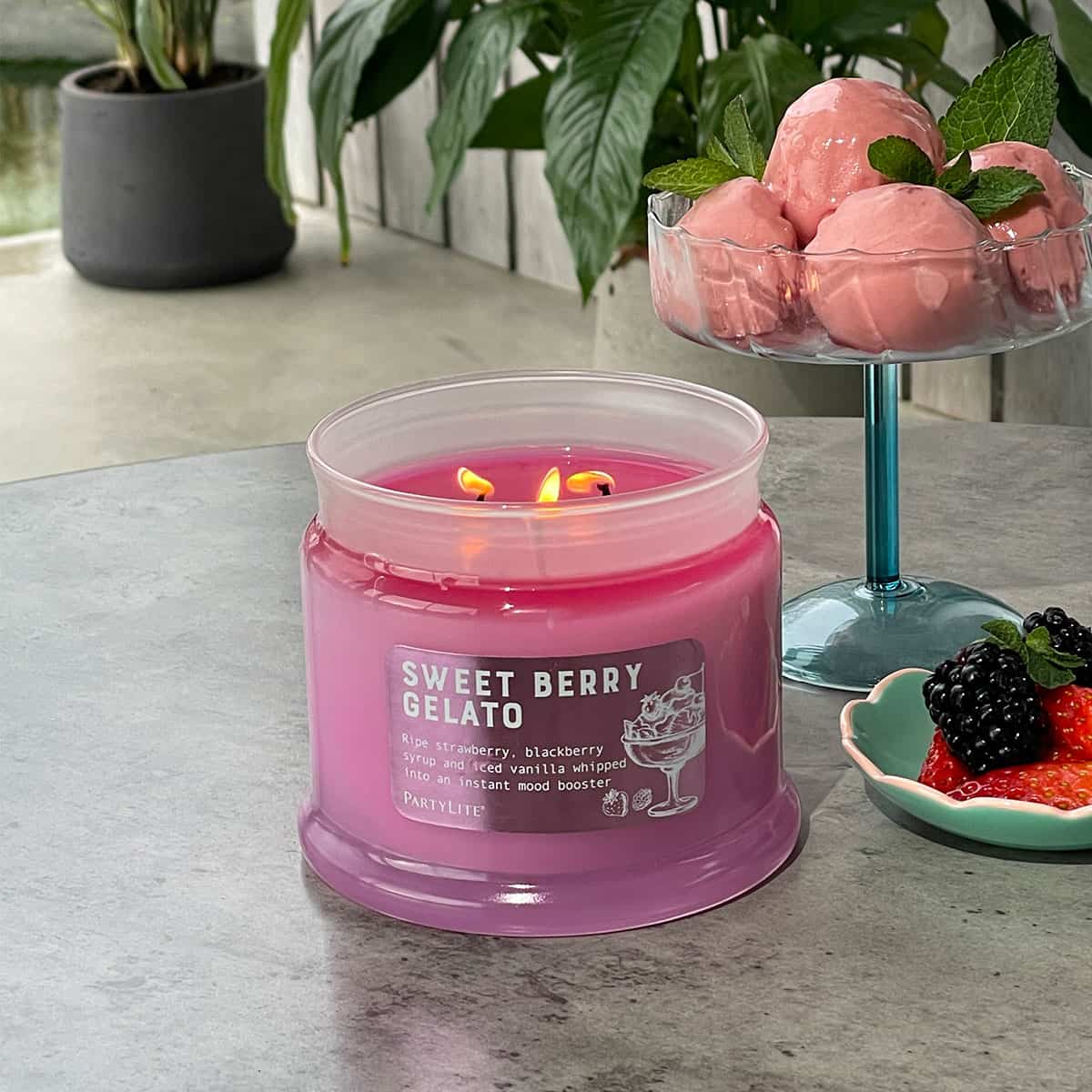 Sweet Berry Gelato 3-Wick Jar Candle lit on a outside table with a bowl of berries and another bowl of ice cream.