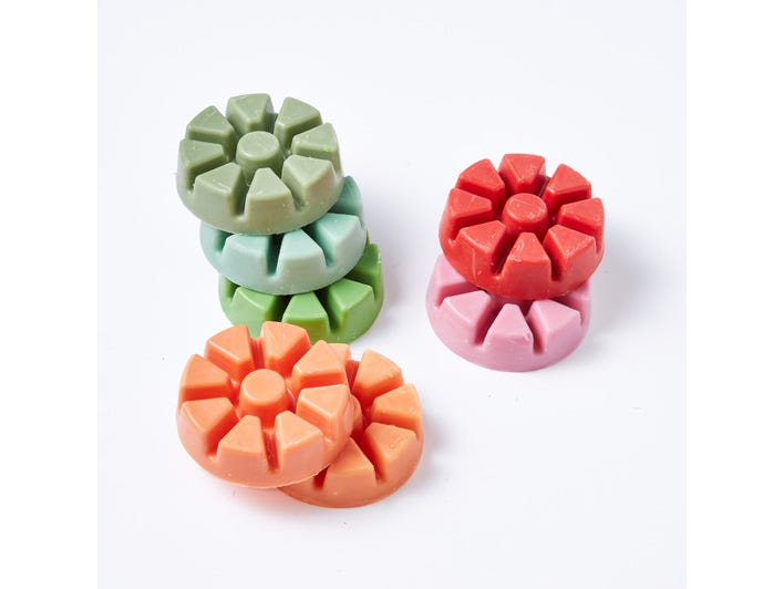 Various colored wax melts, in pink,green,orange against a white background.