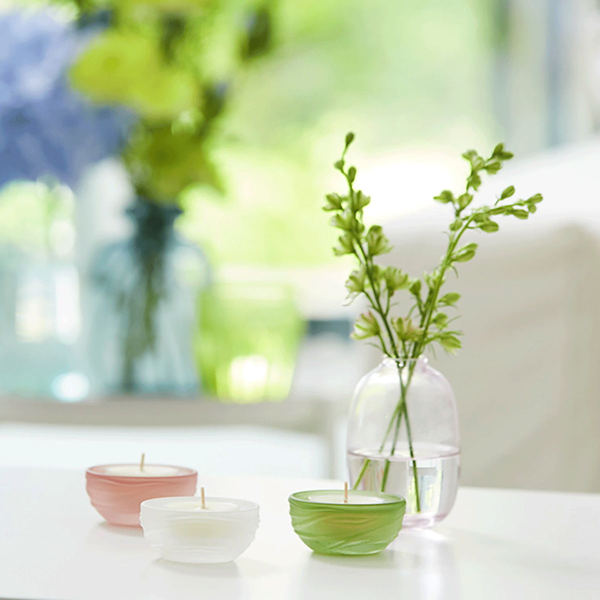 Bird's Nest Tealight Candle Holder Trio shown with tealights on a light colored surface with a blurred background.