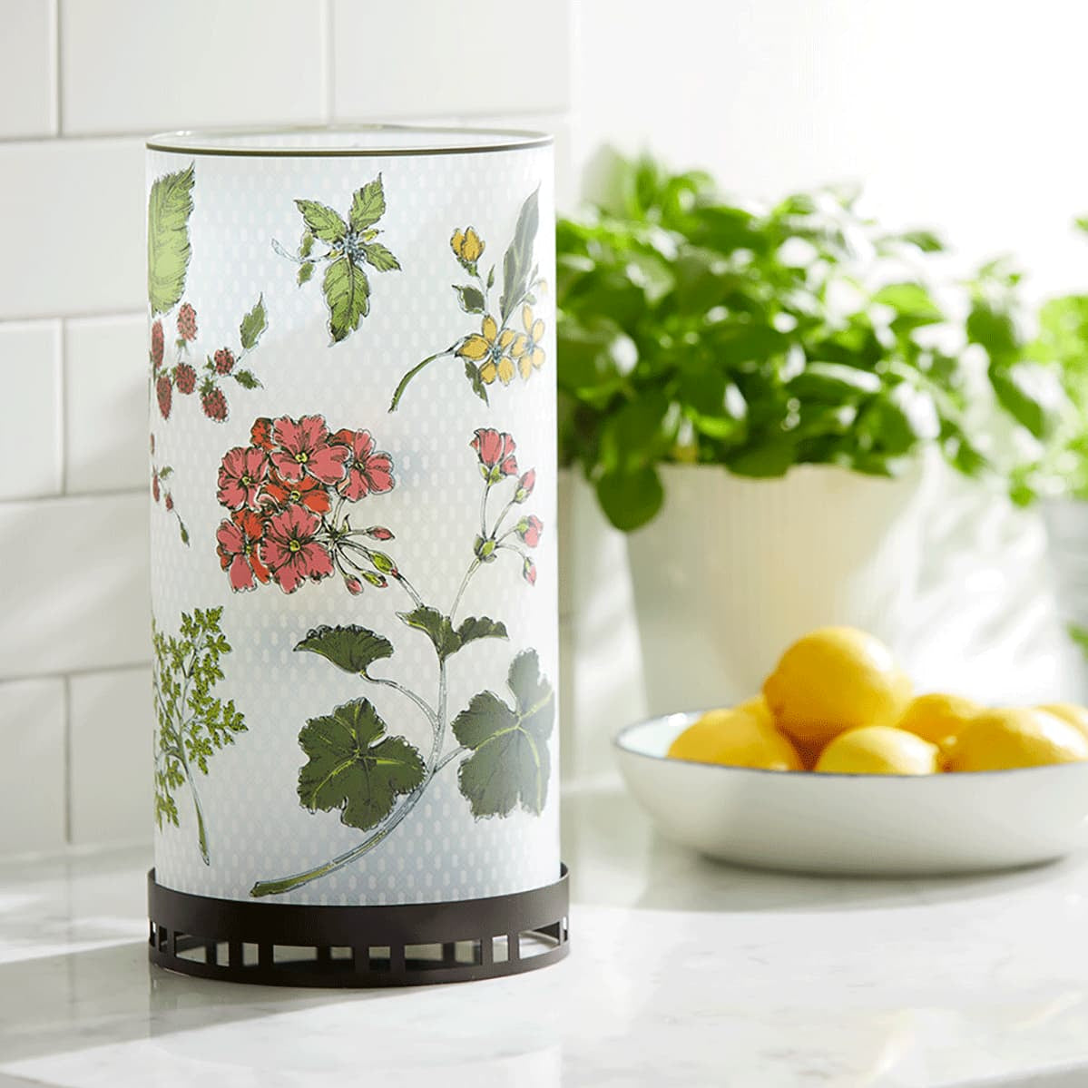 Fresh Garden Mix Hurricane with red and yellow colored flowers and green leaves. on a kitchen work surface next a bowl of lemons.