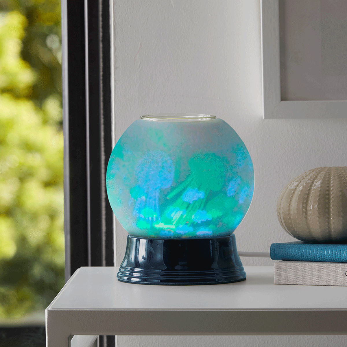 Under the Sea scentglow warmer, with blue and green jelly fish when switched on, on a table.